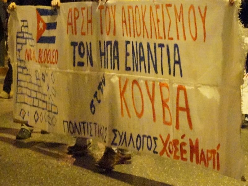Φωτογραφία: Πανό "Άρση των αποκλεισμών των ΗΠΑ ενάντια στην Κούβα Πολιτιστικός Σύλλογος Χοσέ Μαρτί" με την κουβανική σημαία και ένα τοίχος να γκρεμίζεται με το σύνθημα "No blooded"