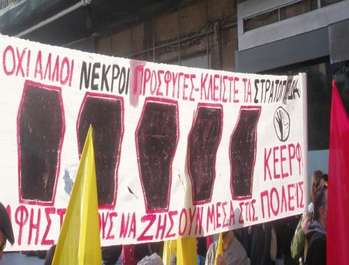 Φωτογραφία: Πανό της ΚΕΕΡΦΑ έχει ζωγραφισμένα πέντε φέρετα. Γράφει πάνω με κεφαλαία κόκκινα γράμματα: ΟΧΙ ΑΛΛΟΙ ΝΕΚΡΟΙ ΠΡΟΣΦΥΓΕΣ- ΚΛΕΙΣΤΕ ΤΑ ΣΤΡΑΤΟΠΕΔΑ (το "νεκροί" και το "στρατόπεδα" είναι με μαύρο). Κάτω γράφει: ΑΦΗΣΤΕ ΤΟΥΣ ΝΑ ΖΗΣΟΥΝ ΣΤΤΙΣ ΠΟΛΕΙΣ. Γύρω από το πανό φαίνονται κίτρινες (ΚΕΕΡΦΑ) σημαίες και μια κόκκινη.